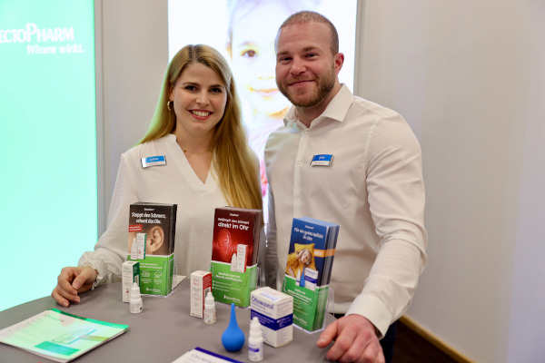 Rückblick auf das pädia Pädiatrie-Event: Zwei lächelnde InfectoPharm-Mitarbeiterinnen und -Mitarbeiter stehen am InfectoPharm-Stand. Auf dem Tisch sind mehrere Produkte zur Ohrenpflege und Ohrengesundheit ausgestellt, darunter Otodolor und Otowaxol, begleitet von Informationsmaterialien. Im Hintergrund ist das InfectoPharm-Logo mit dem Slogan "Wissen wirkt." zu sehen.