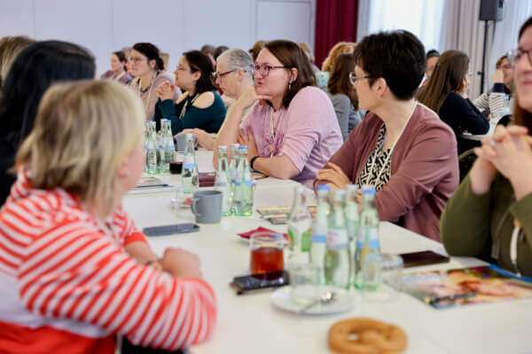 Rückblick auf das pädia Pädiatrie-Event: Zahlreiche Teilnehmerinnen sitzen an langen Tischreihen in einem hell erleuchteten Veranstaltungssaal und verfolgen aufmerksam das Programm. Auf den Tischen stehen Wasserflaschen und Getränke. Im Vordergrund sind pädia-Broschüren zu erkennen.Rückblick auf das pädia Pädiatrie-Event: Zahlreiche Teilnehmerinnen sitzen an langen Tischreihen in einem hell erleuchteten Veranstaltungssaal und verfolgen aufmerksam das Programm. Auf den Tischen stehen Wasserflaschen und Getränke. Im Vordergrund sind pädia-Broschüren zu erkennen.
