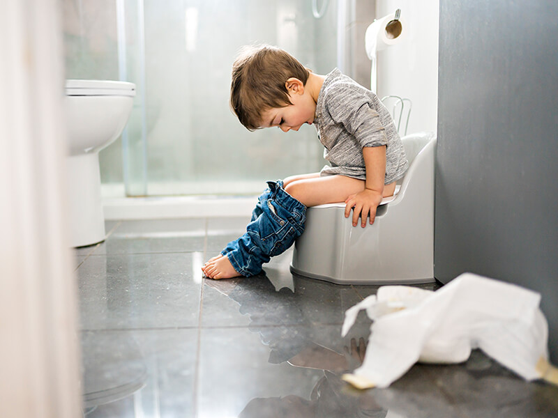 Kind sitzt auf der Toilette