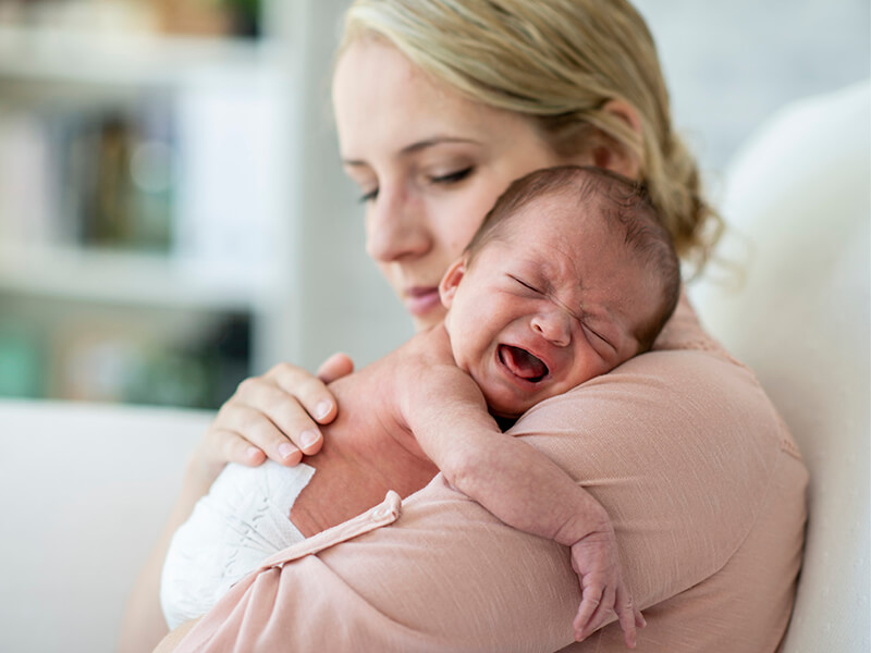 Baby schreit auf dem Arm von der Mutter